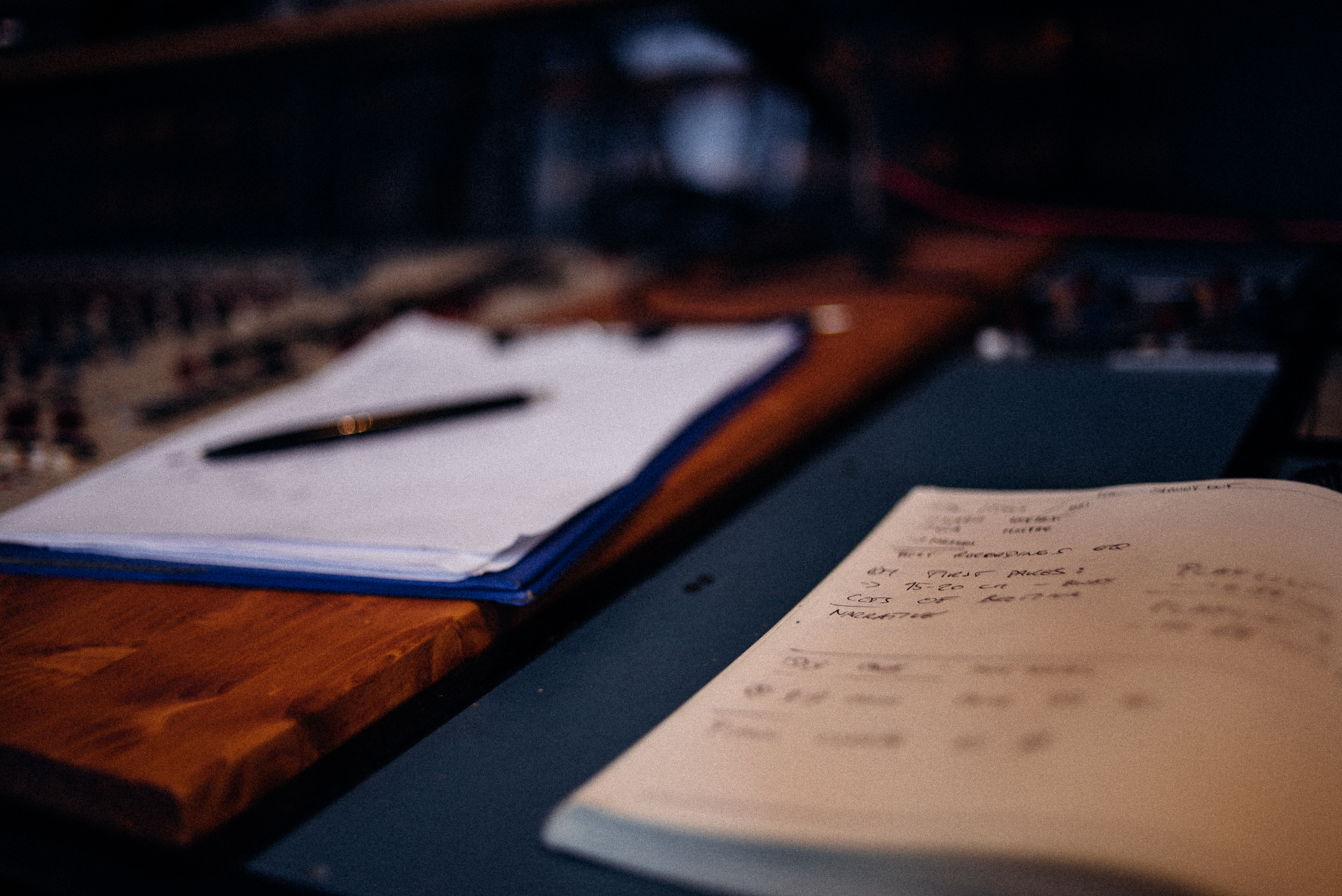 Notebook with handwritten session notes and a script with a pen on a mixing console